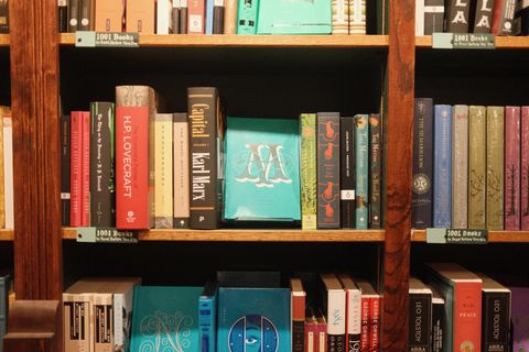 A photograph of a bookshelf with a centere book cover facing forward. It has a large ornate M on it for Moby Dick.