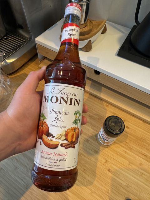 Picture of me holding pumpkin spice syrup at my coffee station